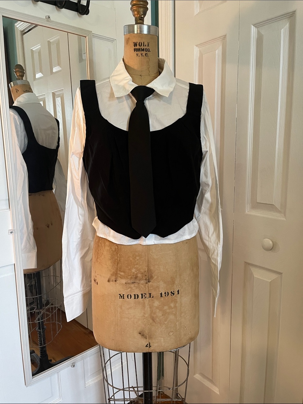 Black Sleeveless Button-Down Crop Vest over White Shirt with Black Tie